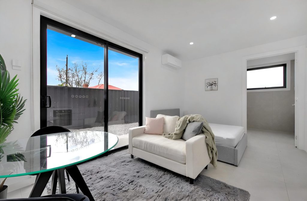 A room at the Deer Park rooming house with a double bed, sofa and sliding door